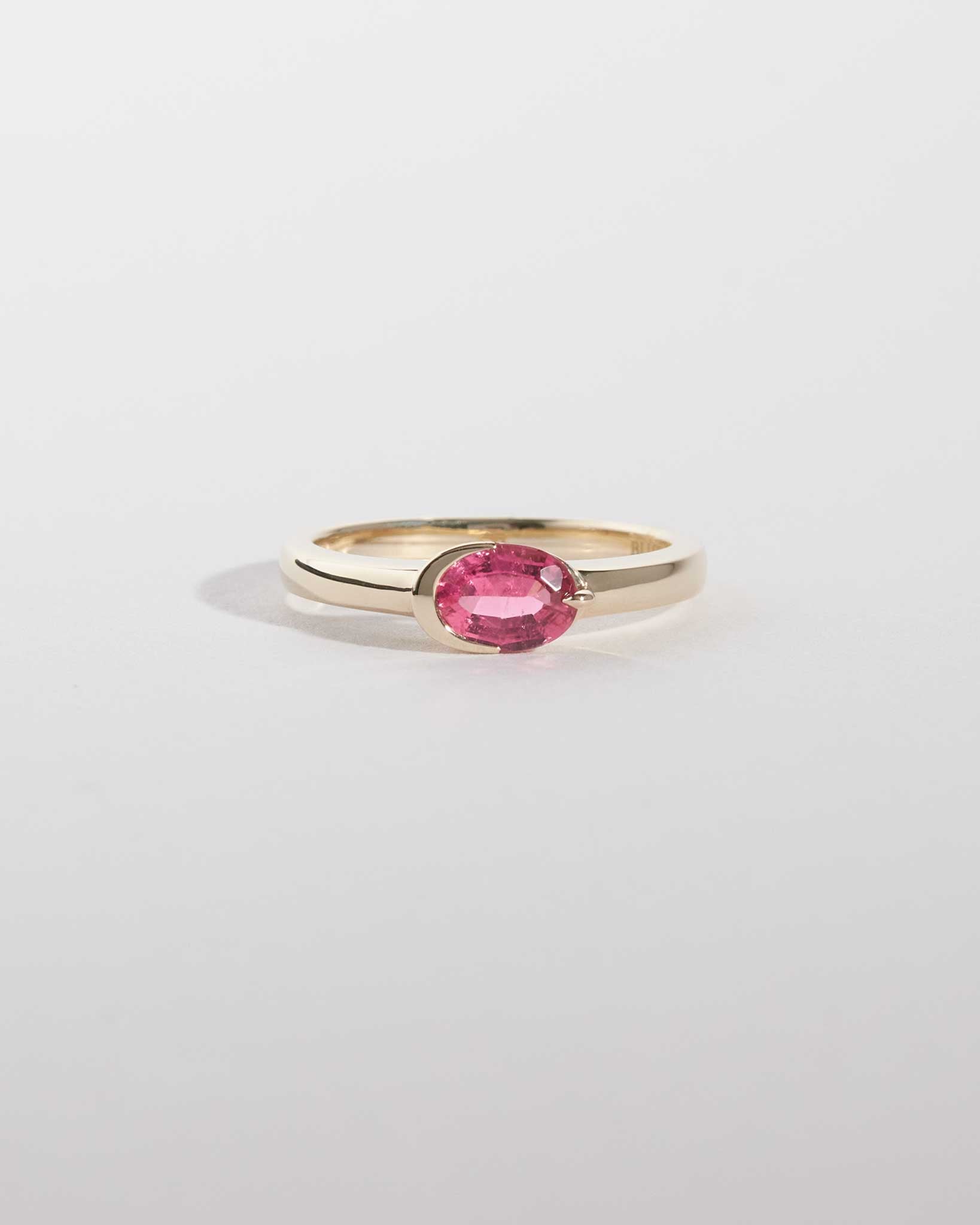 Gold ring with a pink gemstone on a light gray background