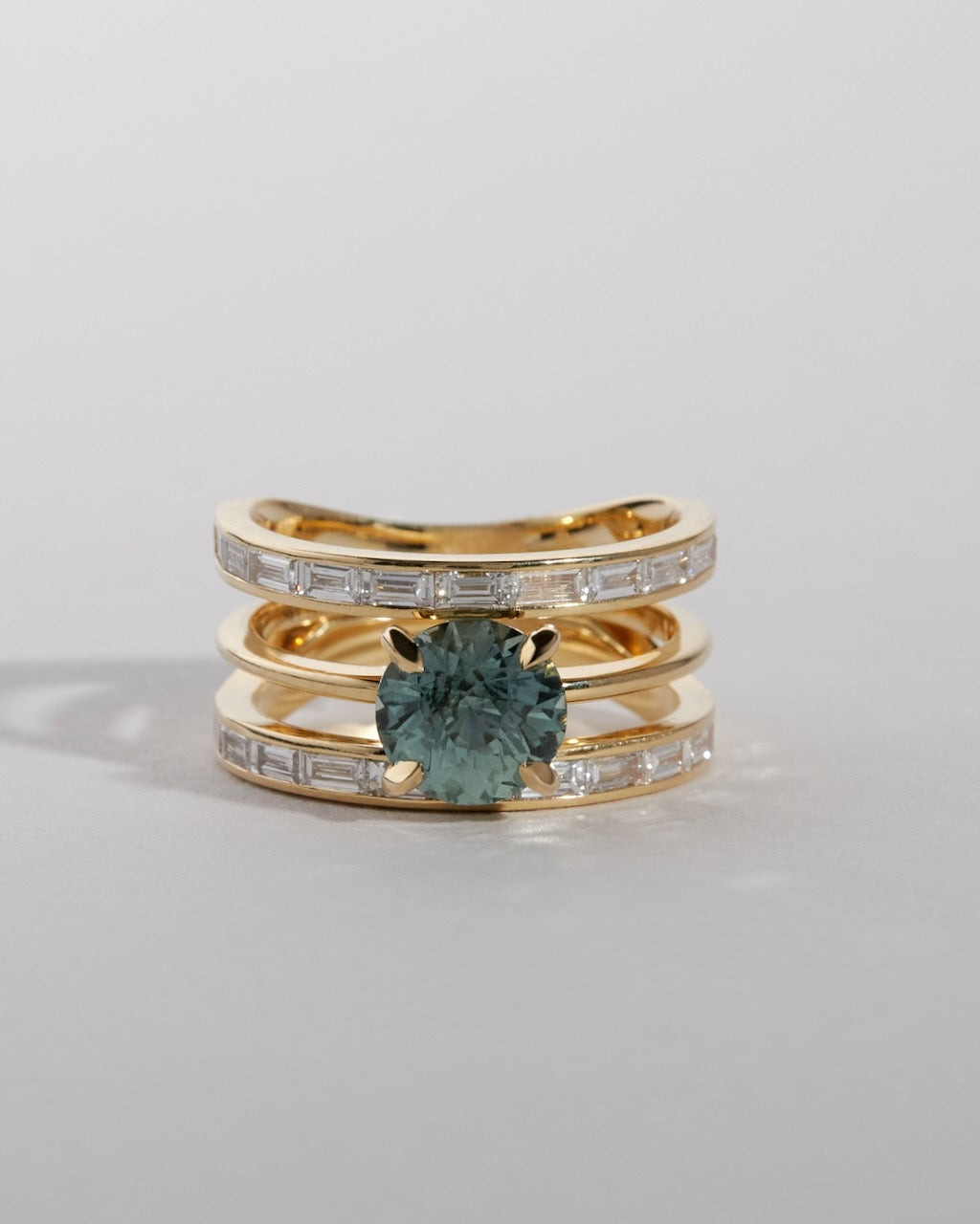 Gold ring with a green gemstone on a light gray background