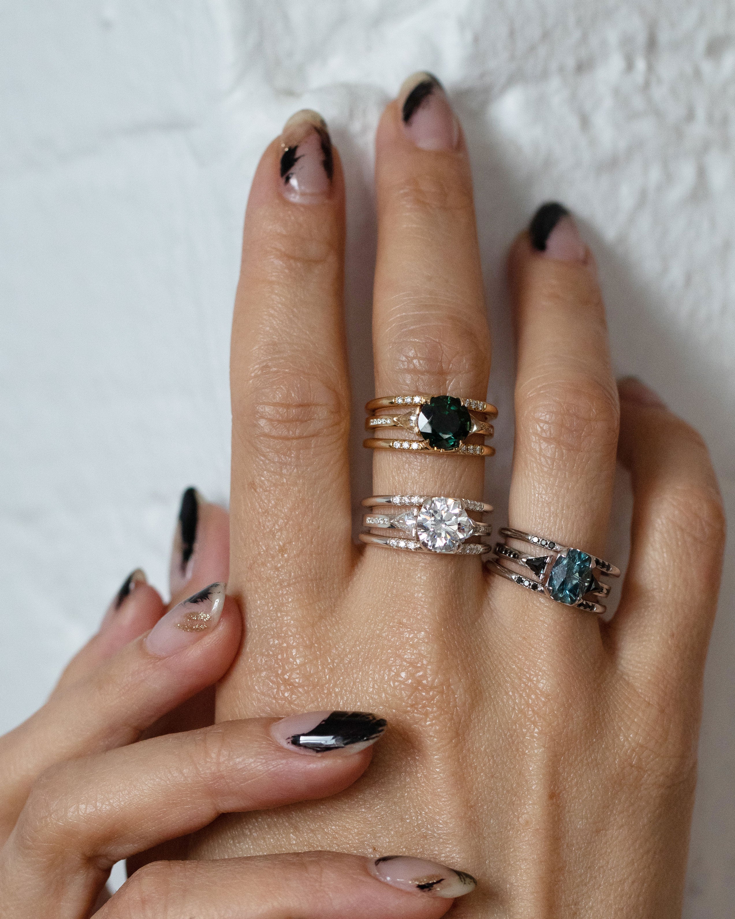 A hand with three different Bliss Lau Illuminate and magnetic ring sets. 