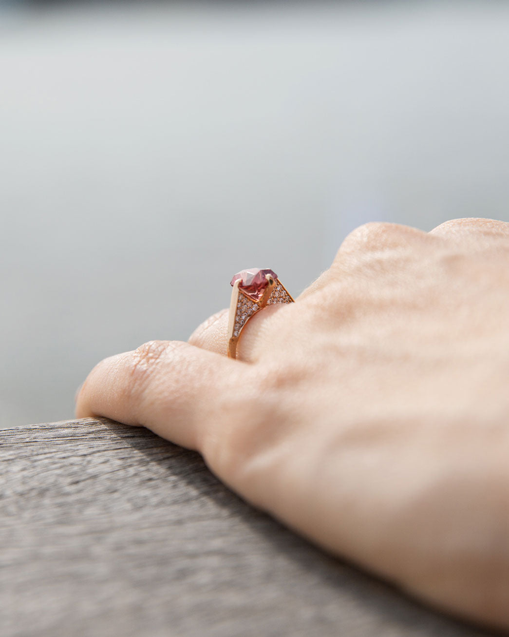 Close-up view of the Hidden Pave Engagement Ring resting on a wooden surface, highlighting the delicate diamond setting and artistry of the piece.